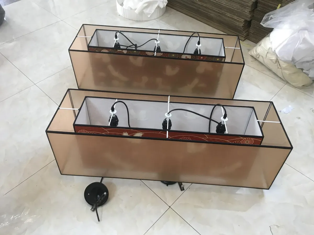 Khung chao đèn hình chữ nhật lộ kết cấu bên trong tại xưởng, cho thấy mối hàn và đui đèn trước khi bọc vải